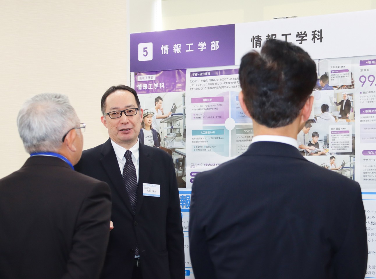 写真：女性の大学職員と資料を見ながら話している2人の男子学生
